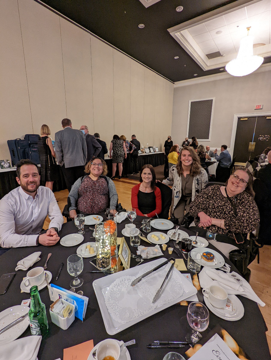 Five people at a circular banquet table, all smiling at the camera.